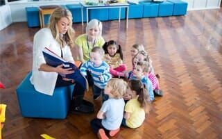 A woman is reading a book to a group of children.
