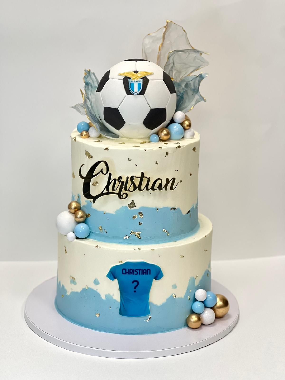 Torta di compleanno a due piani decorata con il tema dei camion, raffigurante un camion blu, cartelli stradali e il nome