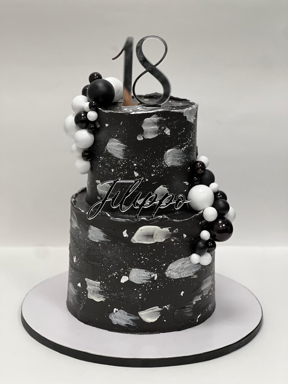 Una torta rotonda con un coniglietto in cima e decorazioni floreali. Sul davanti è scritto