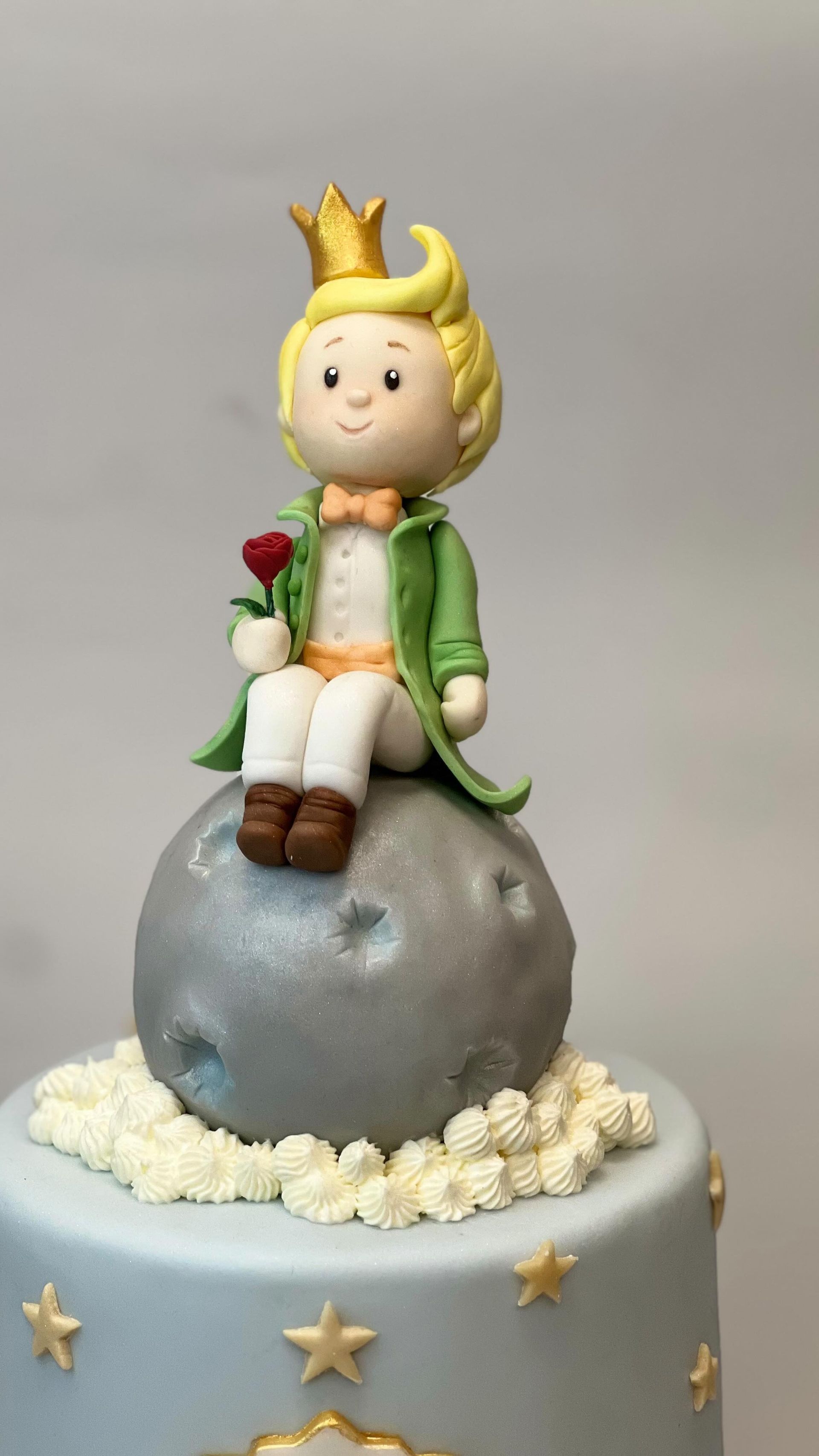 Decorazione per torta: il Piccolo Principe con una rosa, seduto su una luna, su una torta blu con stelle.