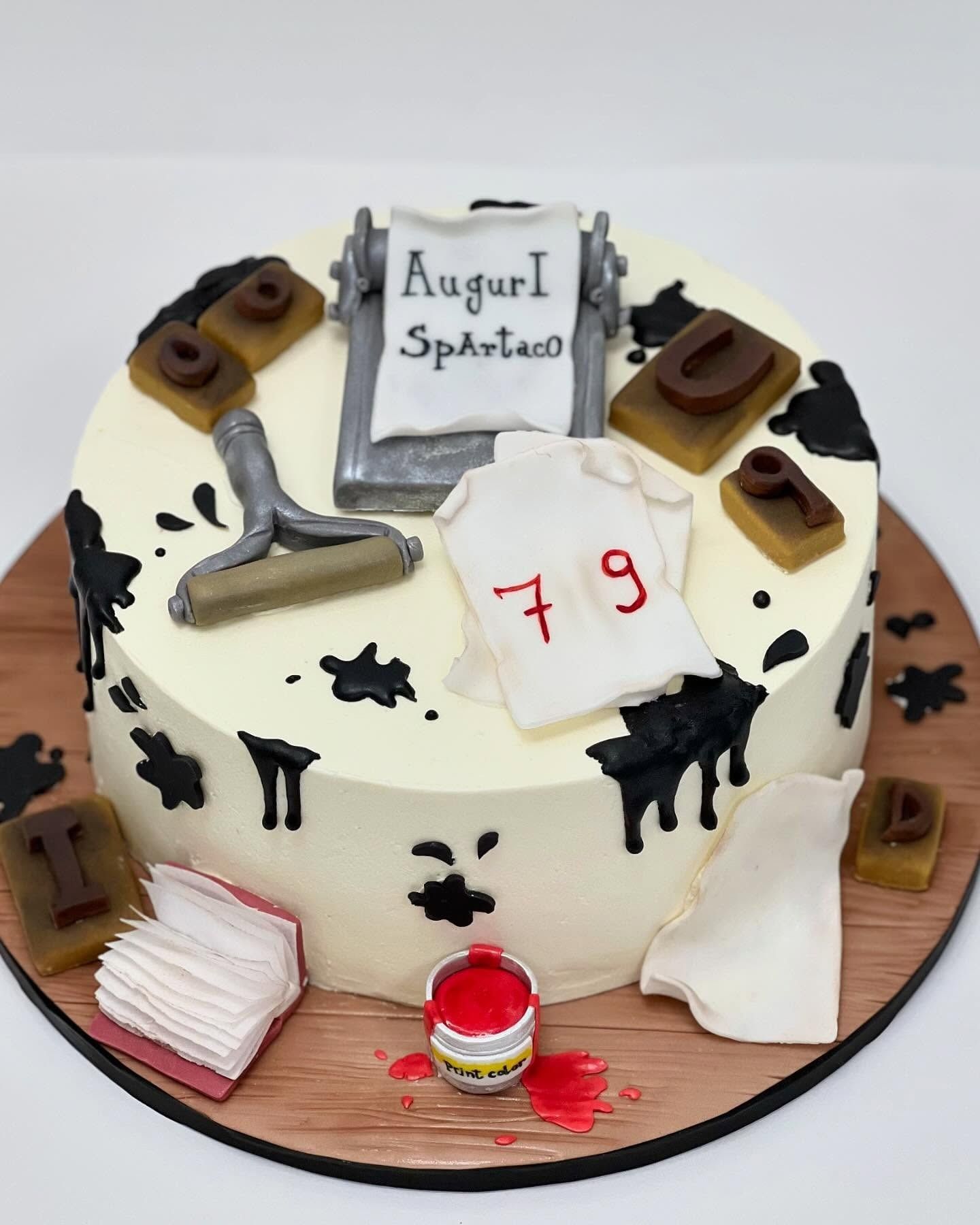 Torta decorata con elementi di stampa: schizzi d'inchiostro, timbri, rullo e una maglietta con la scritta