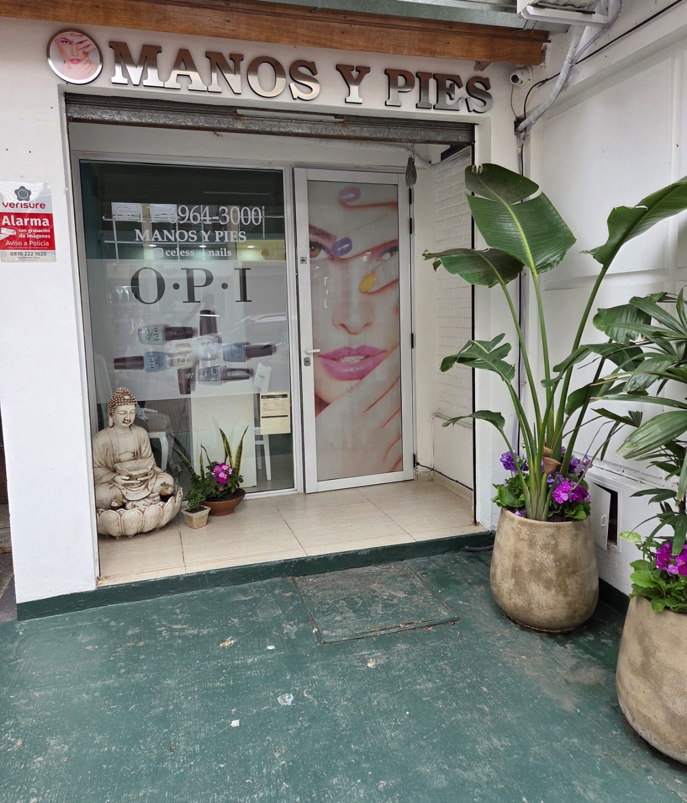 Salón de belleza luminoso y moderno con mesas de manicura, estantes para productos y mostrador de recepción.