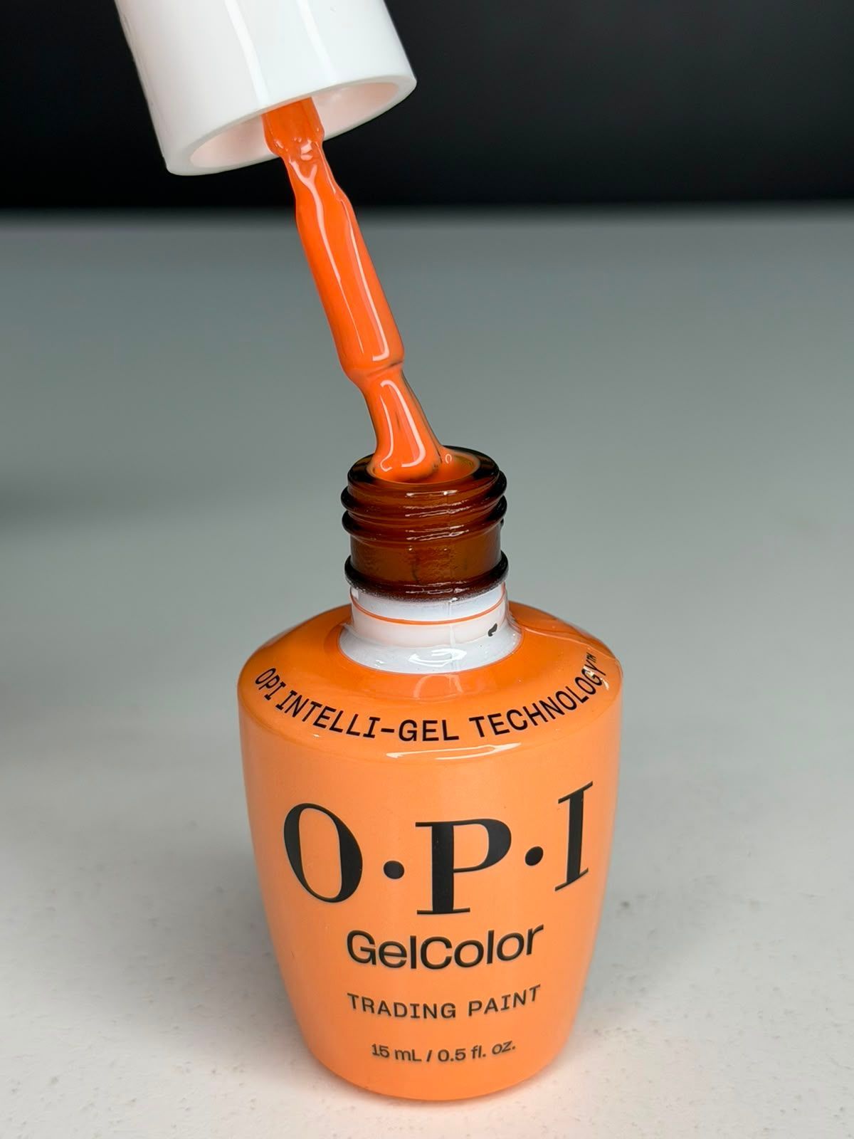 Esmalte de uñas naranja OPI GelColor siendo aplicado con pincel desde el frasco.