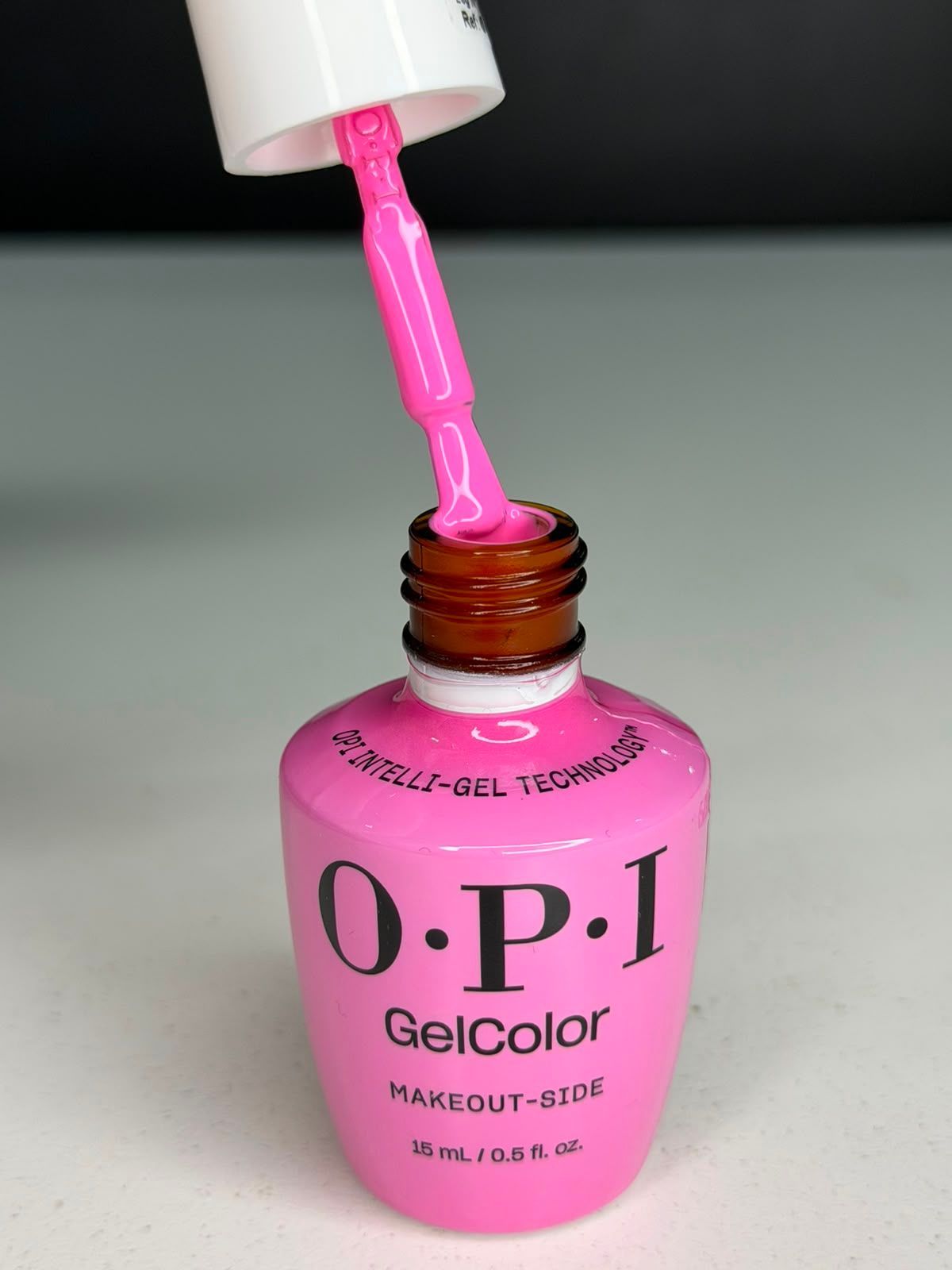 Esmalte de uñas rosa OPI GelColor siendo aplicado con pincel desde el frasco.