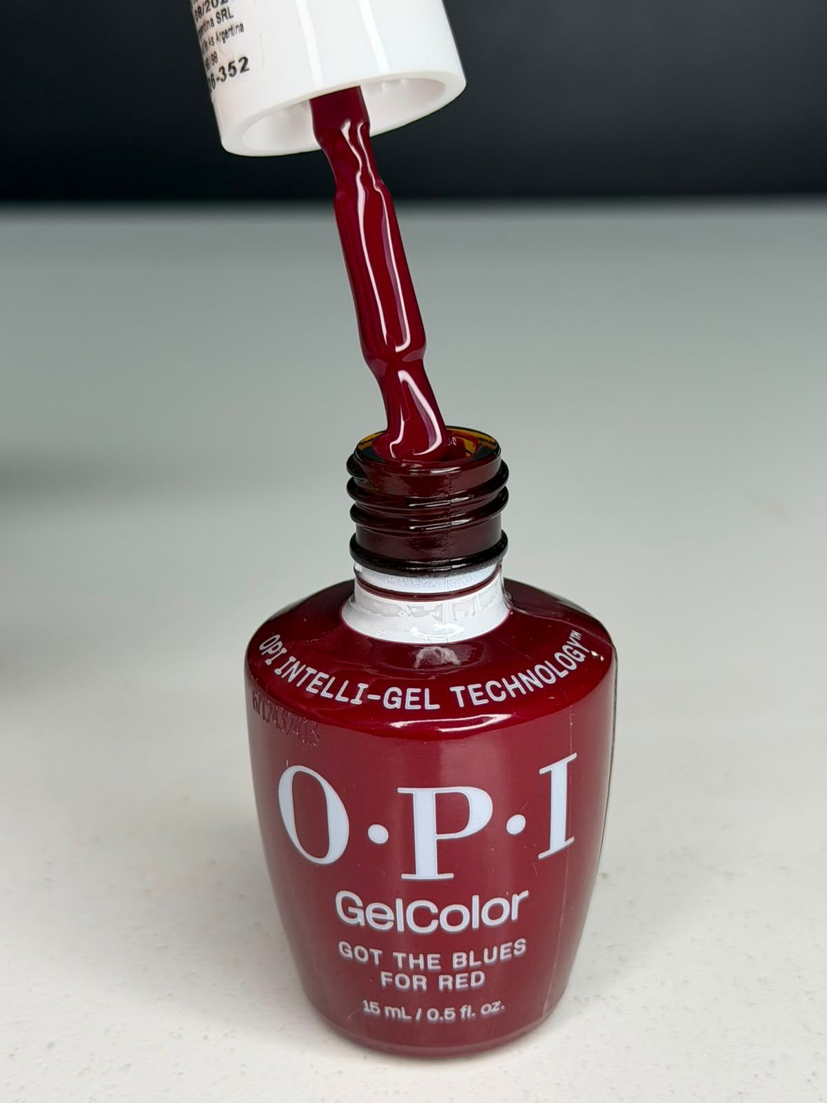 Esmalte de uñas rojo OPI vertiéndose de una botella sobre una superficie.