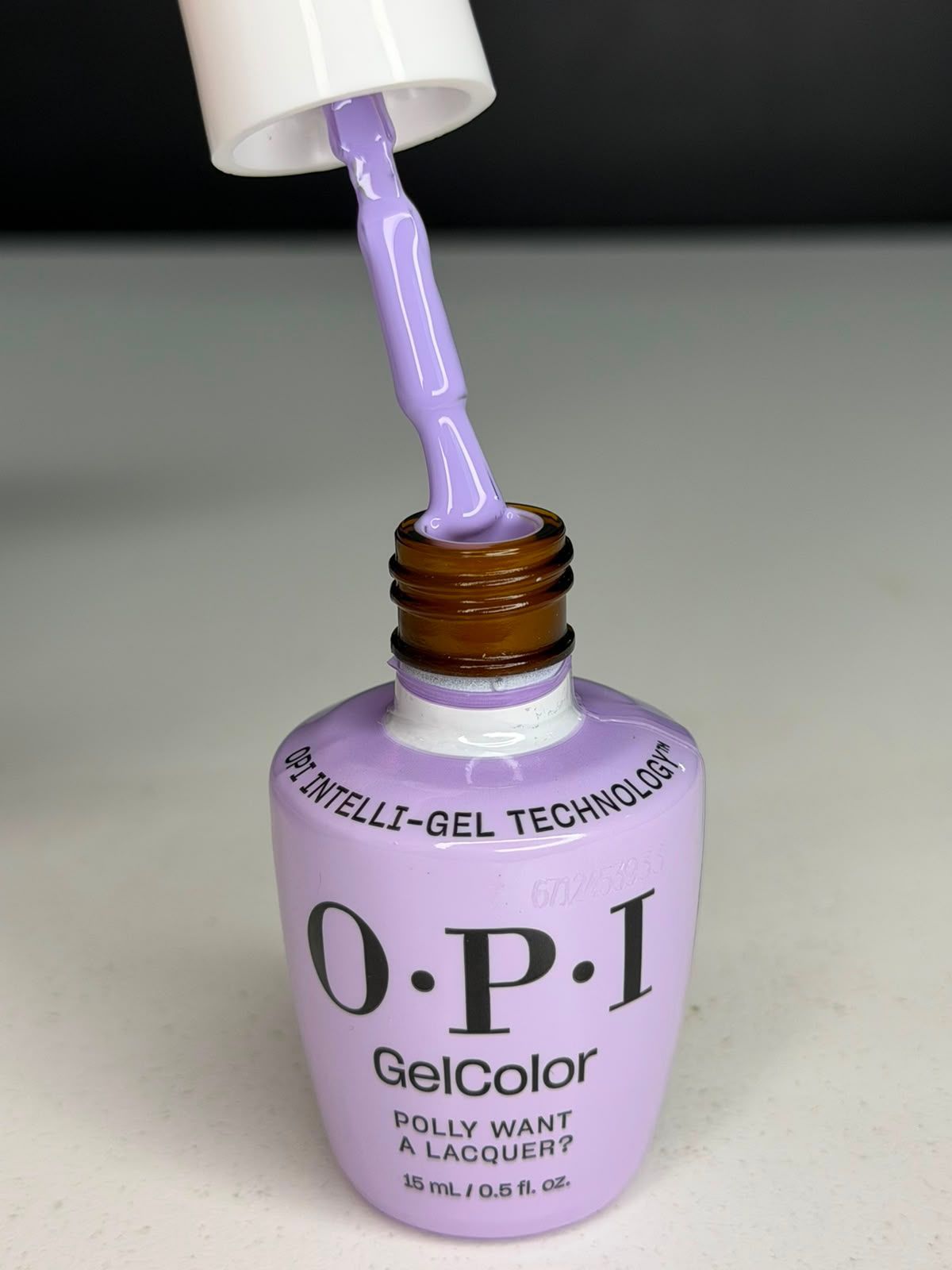 Esmalte de uñas OPI GelColor color lila aplicado con pincel desde un frasco abierto.