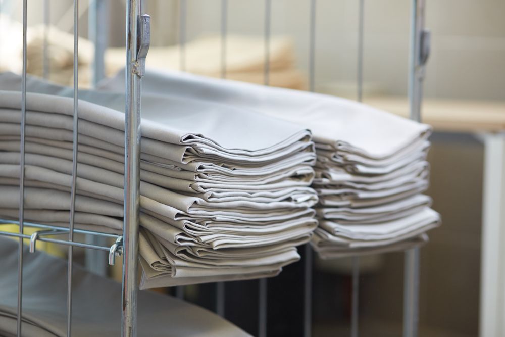 Two Stacks of Folded, Light-grey Linens— Flynns Beach Service Laundry in Thrumster, NSW