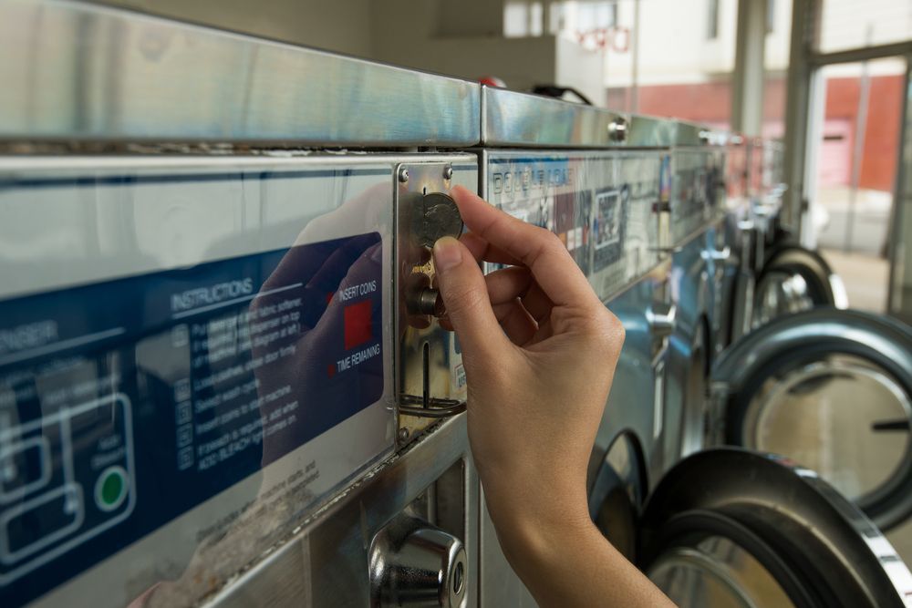 Hand Adjusts the Dial on a Metal Coin-operated Washing Machine — Flynns Beach Service Laundry in Bonny Hills, NSW
