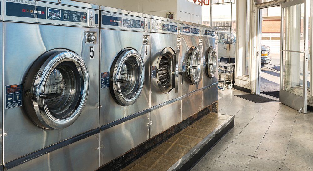 A Row of Stainless Steel Industrial Washing Machines Lined Up — Flynns Beach Service Laundry in Port Macquarie, NSW