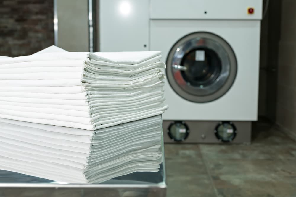 Stack of Folded White Linens in a Laundromat — Flynns Beach Service Laundry in Port Macquarie, NSW