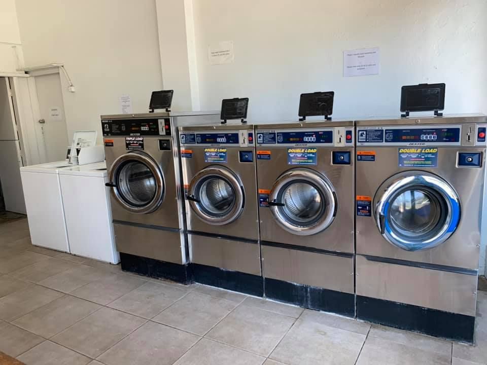 Row of Four Stainless Steel Industrial Washing Machines — Flynns Beach Service Laundry in Port Macquarie, NSW