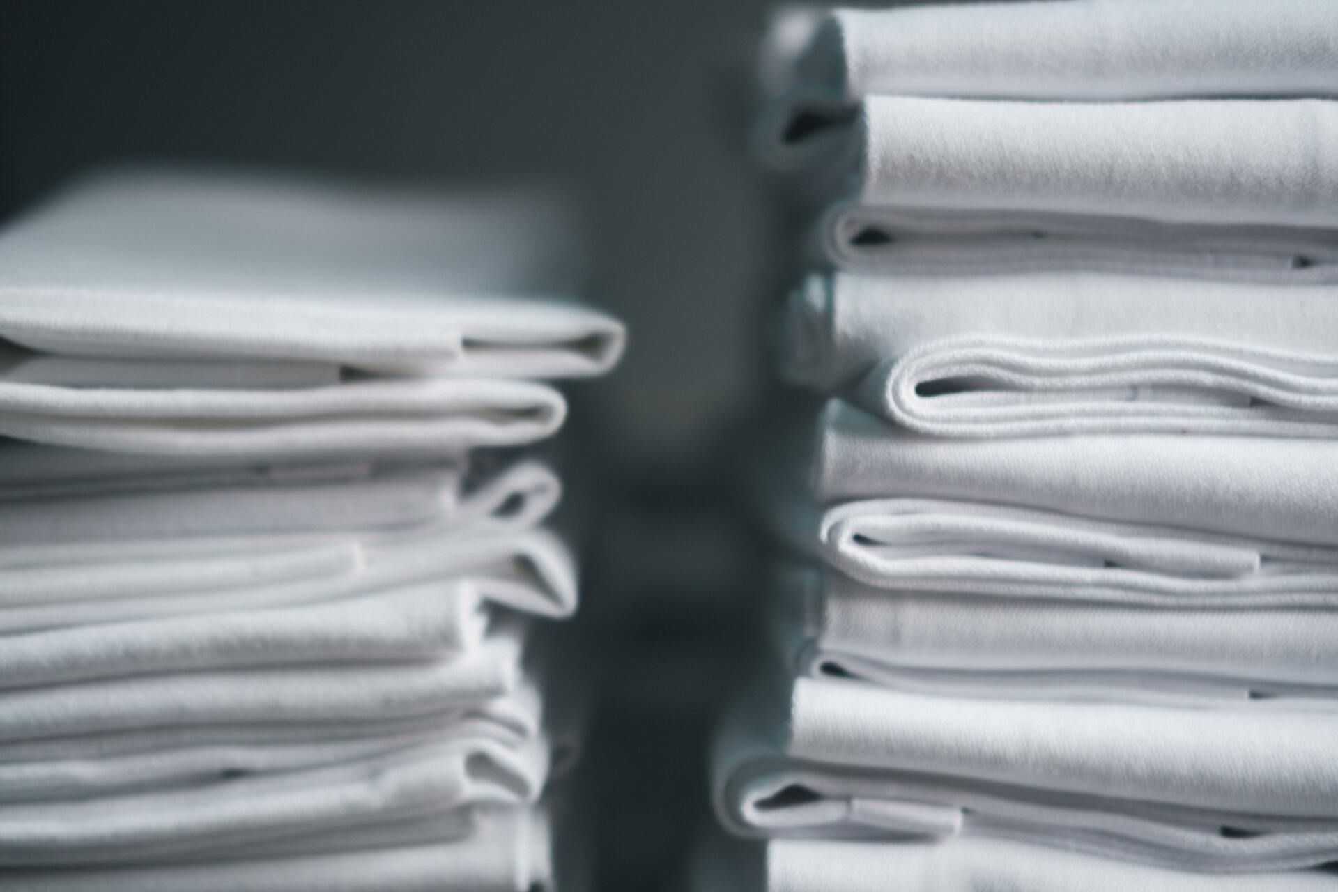 Two Stacks of Neatly Folded White Laundry — Flynns Beach Service Laundry in Port Macquarie, NSW