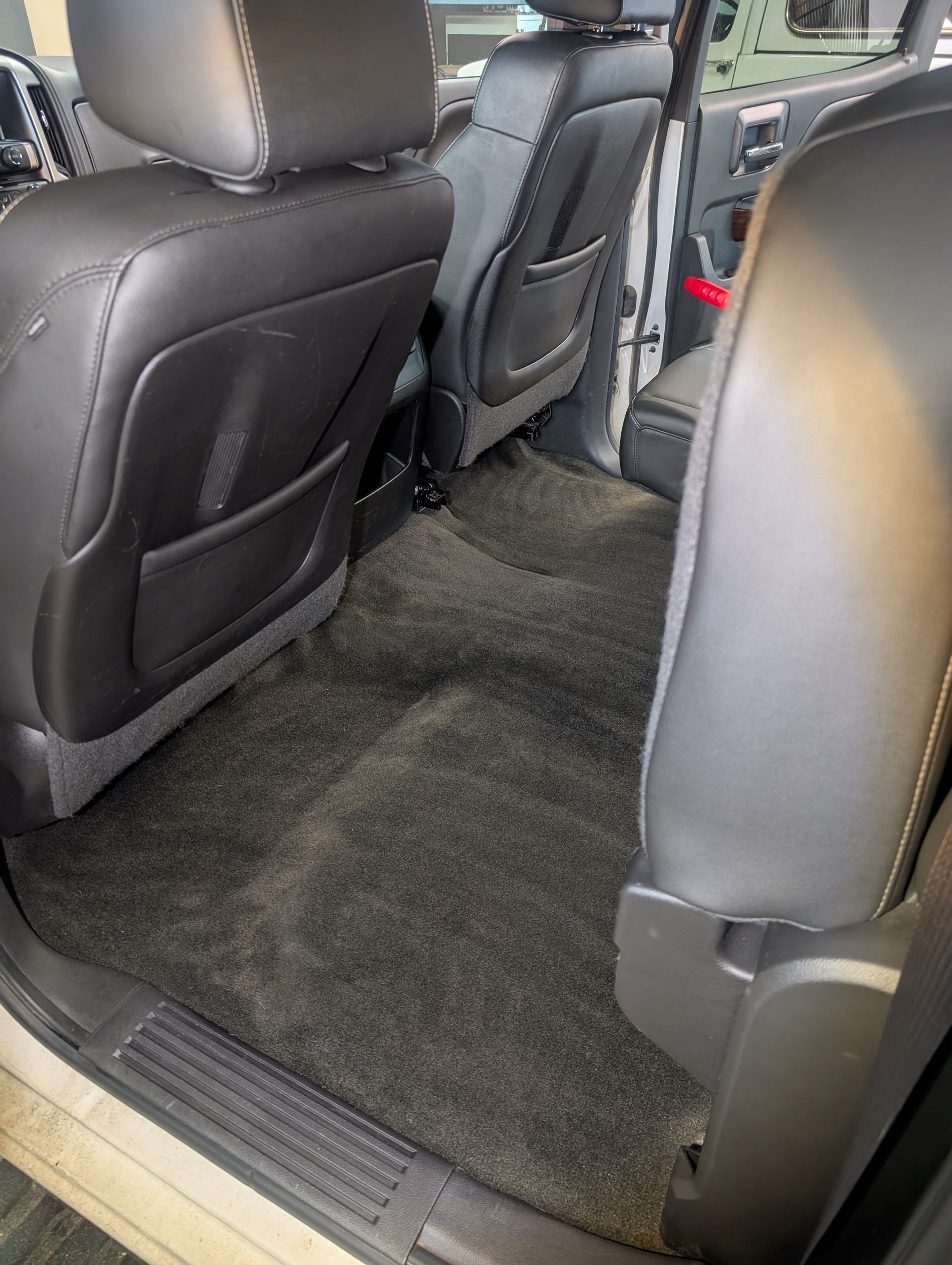 Black leather car seats with black carpet flooring.