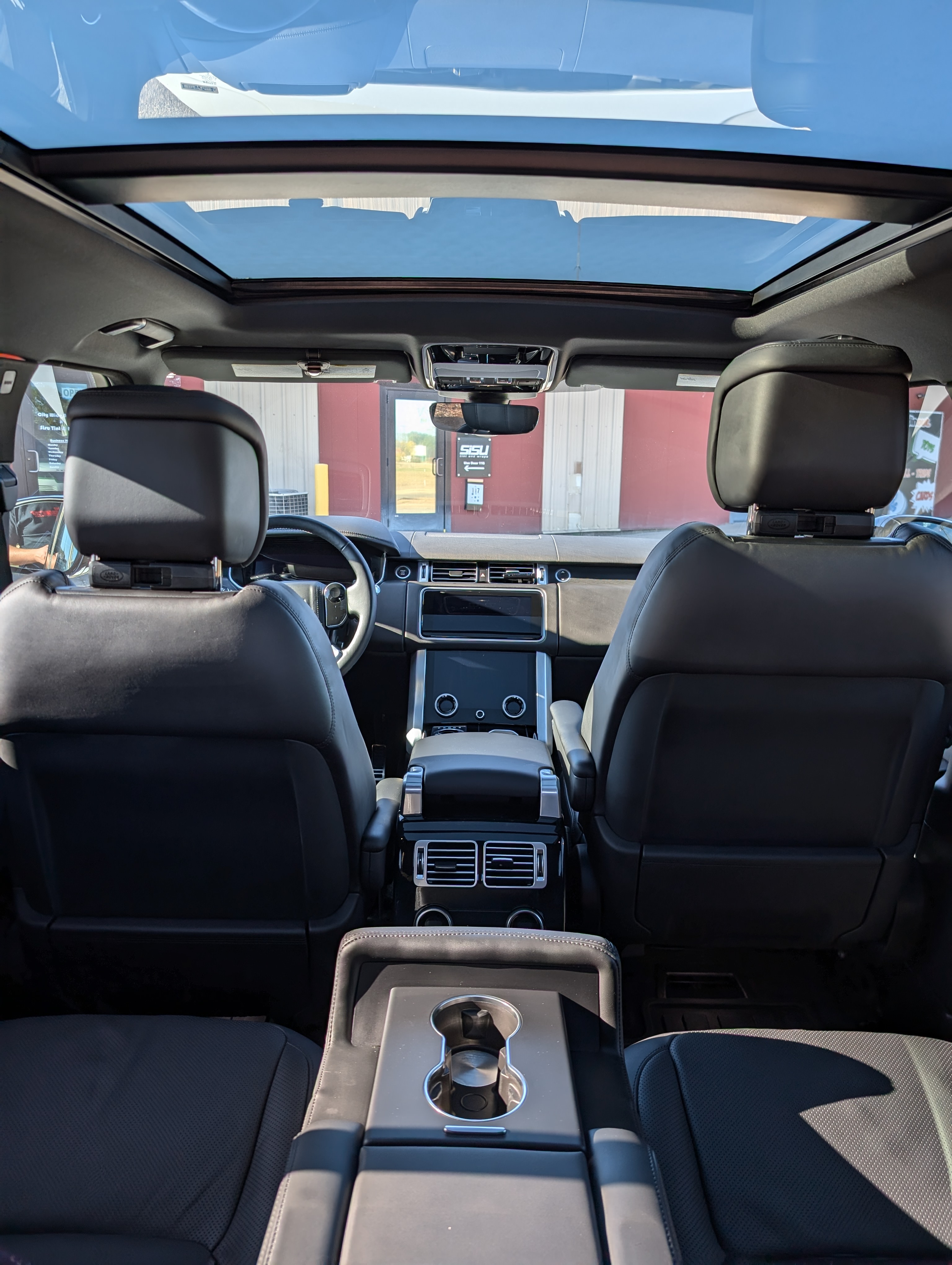 Interior view of a black SUV with a panoramic sunroof; the front seats and dashboard are visible.
