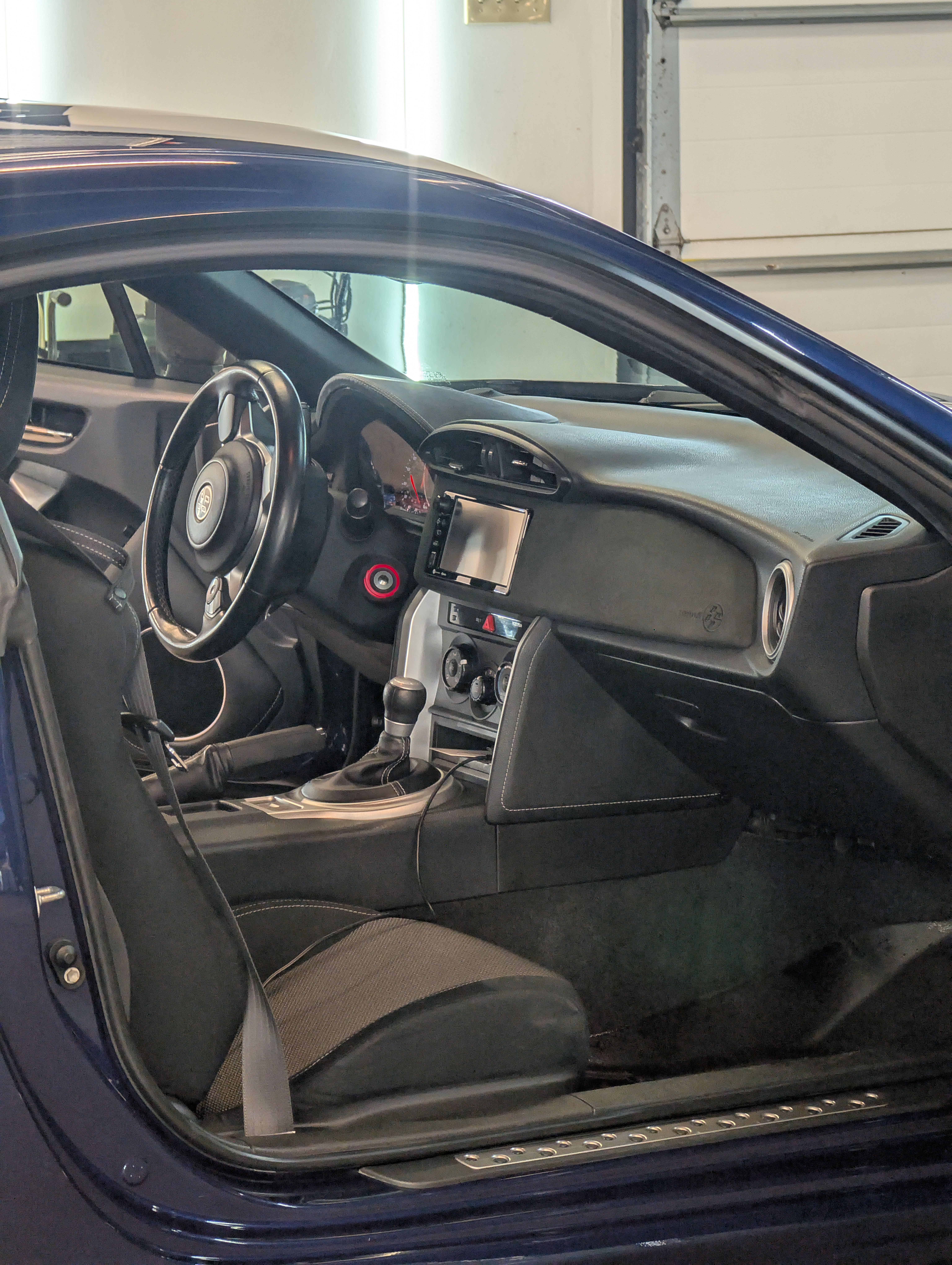 Interior of a blue sports car with black interior; steering wheel, dashboard, and seat visible.