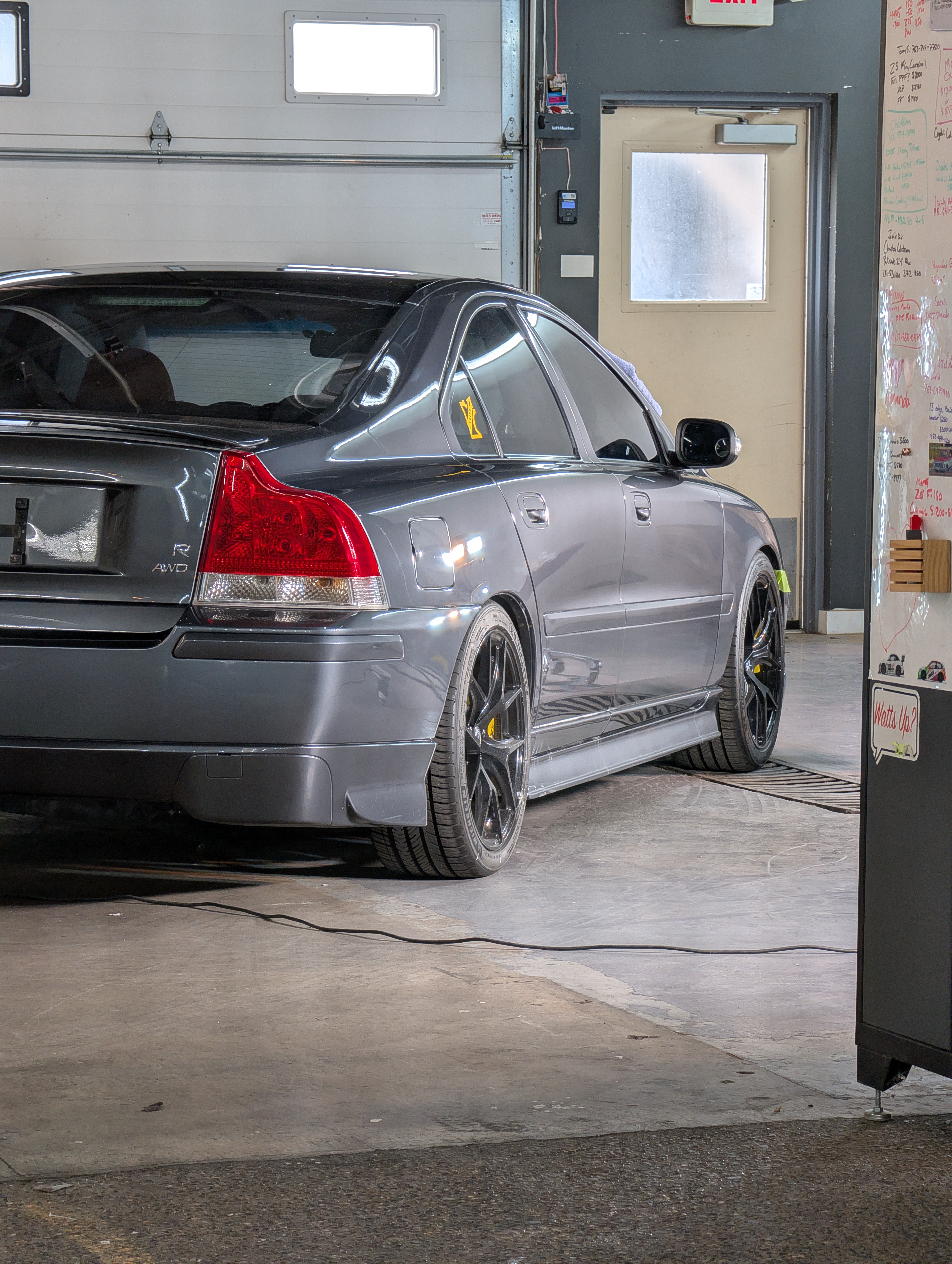 Gray Volvo sedan parked inside a garage, next to a door.