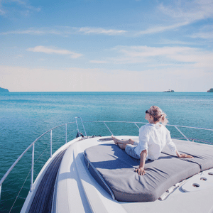 Person relaxing on a yacht bow under a blue sky, looking out over calm turquoise sea