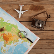 Travel map with a magnifying glass, toy airplane, and vintage camera on a wooden table
