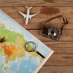 Travel map with a magnifying glass, toy airplane, and vintage camera on a wooden table