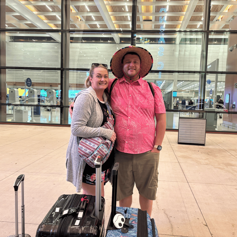 Two people smiling with luggage in an airport terminal