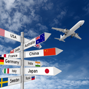 Airport signpost with country arrows and flags under a blue sky; airplane flying overhead