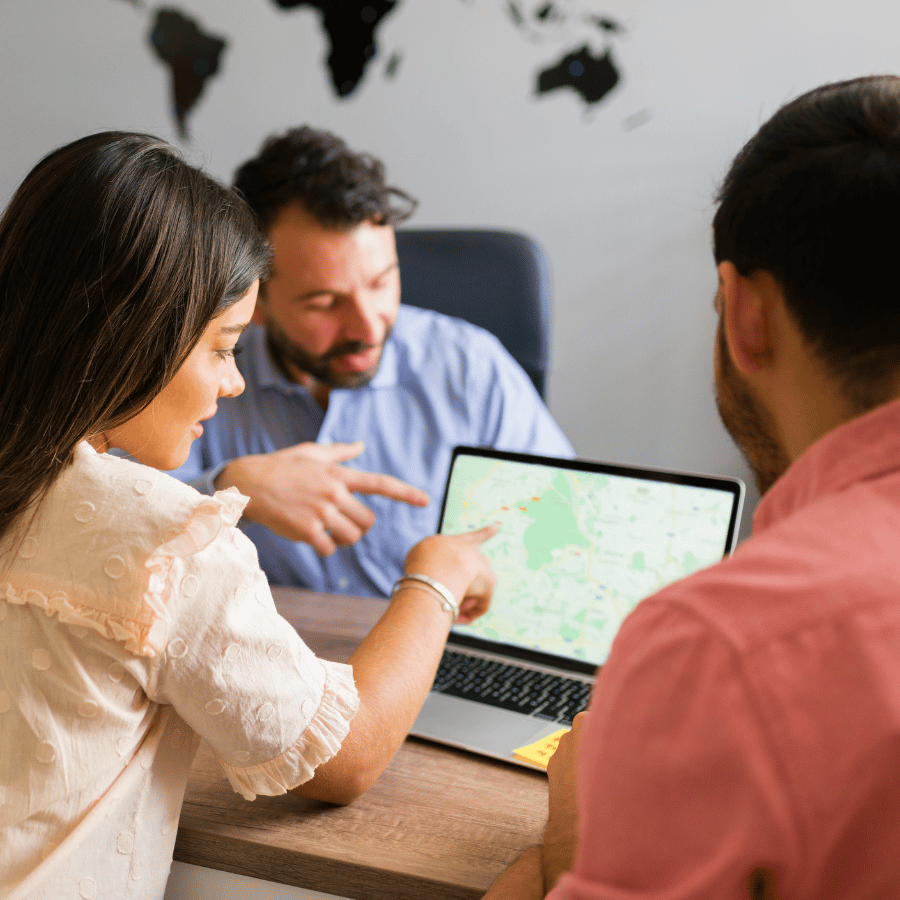 Three coworkers reviewing data on a laptop at a table in a meeting room