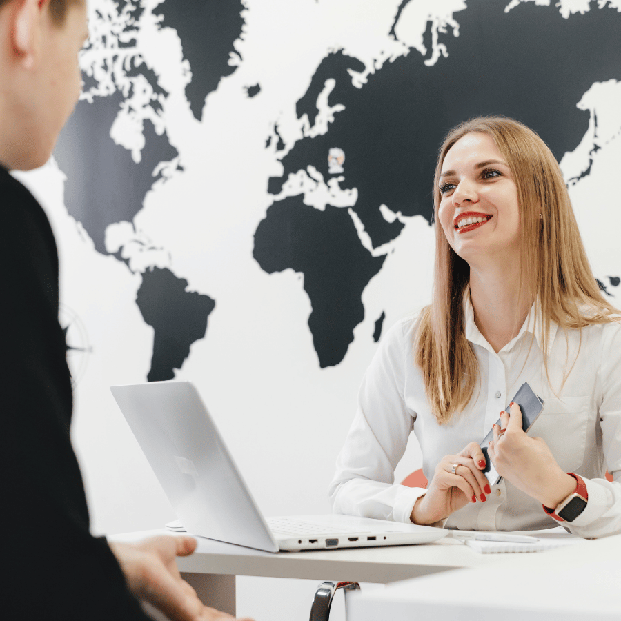 Two people meeting at a desk with a laptop, in front of a black-and-white world map wall