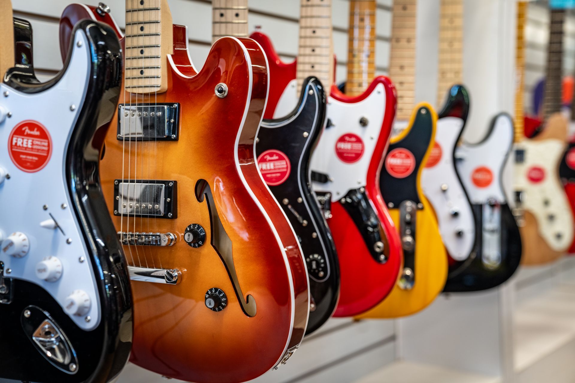 Row of electric guitars in a music store, various colors, hanging on display.
