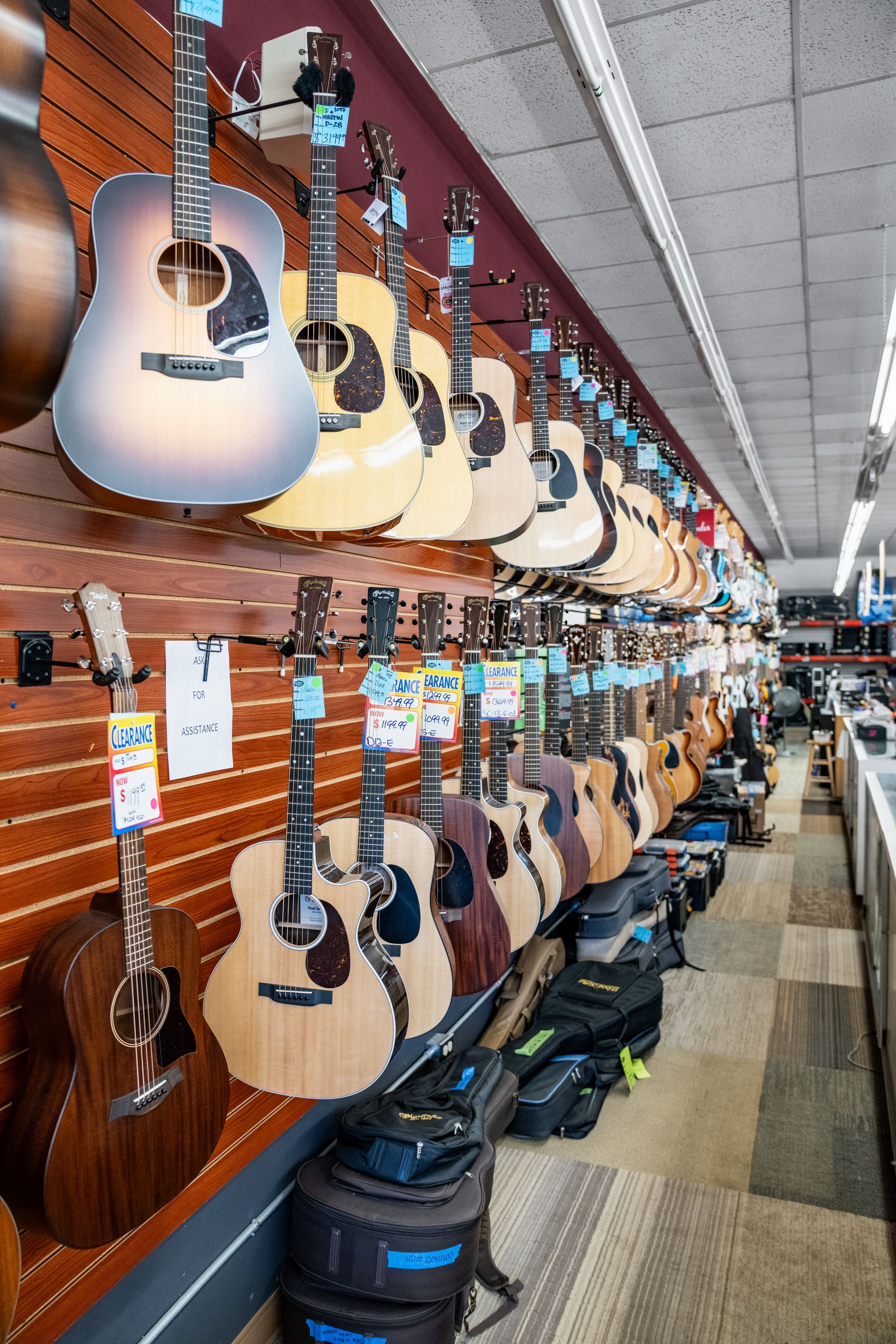 Guitars displayed on a wood-paneled wall inside a music store, with various colors and styles.