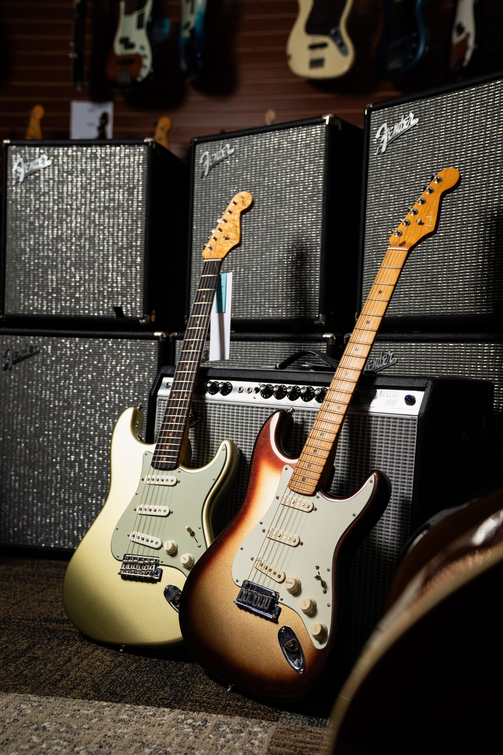 Two electric guitars leaning against Fender amplifiers in a music store.