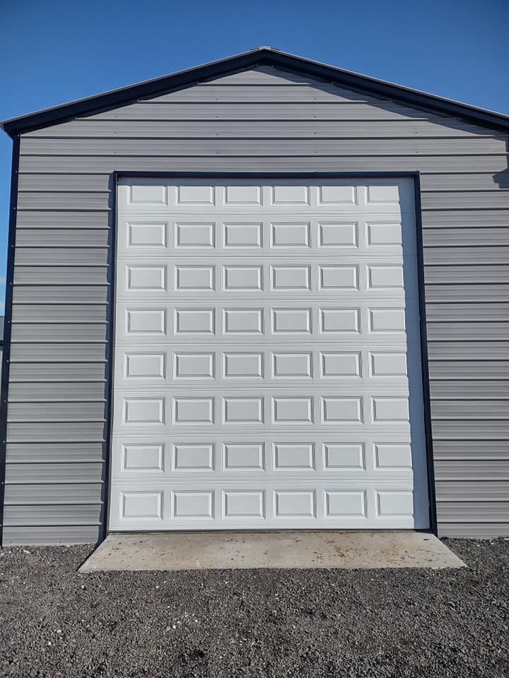 Two brown wooden garage doors on a house under construction, with Tyvek house wrap visible above.