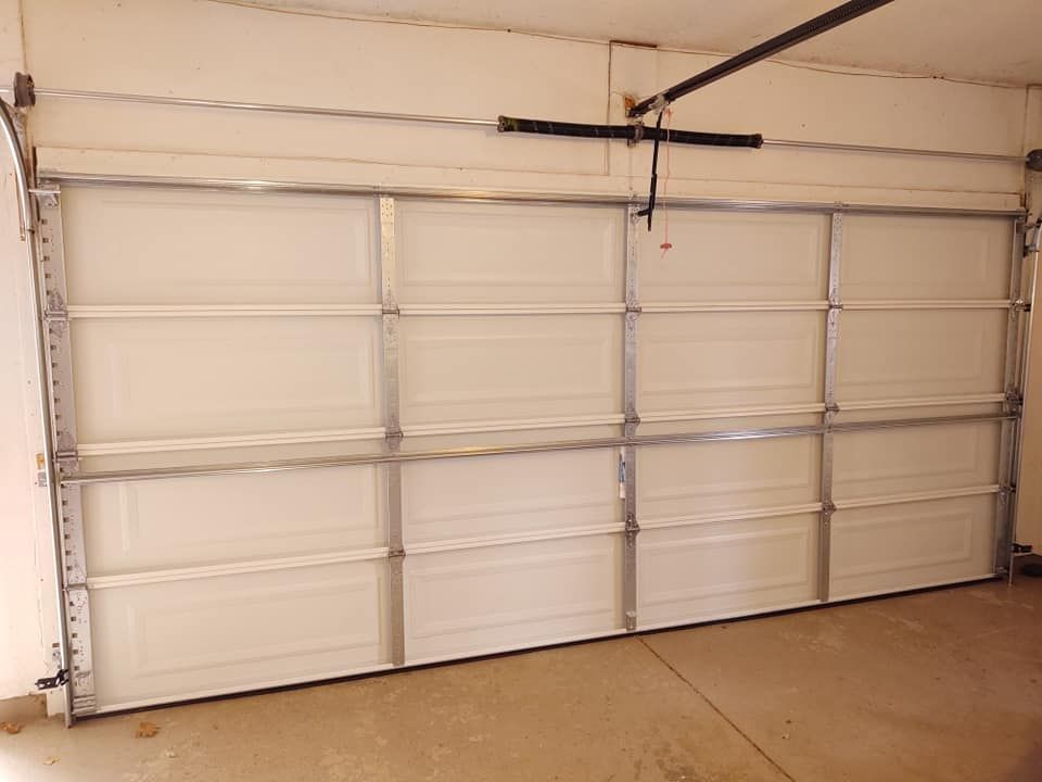 Closed gray sectional garage door with black opener rail and red pull cord on a white ceiling