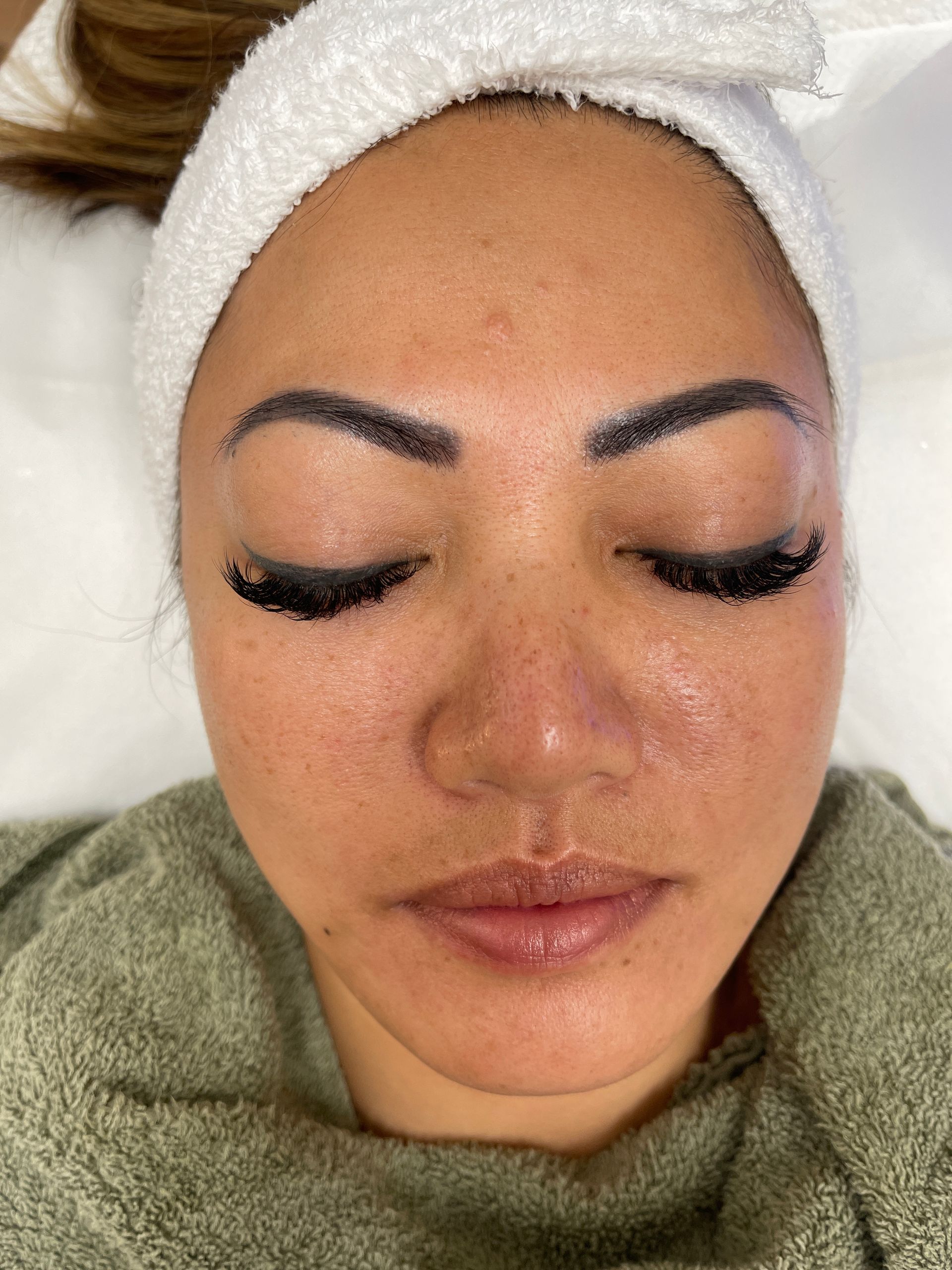A close up of a woman 's face with a towel around her head.