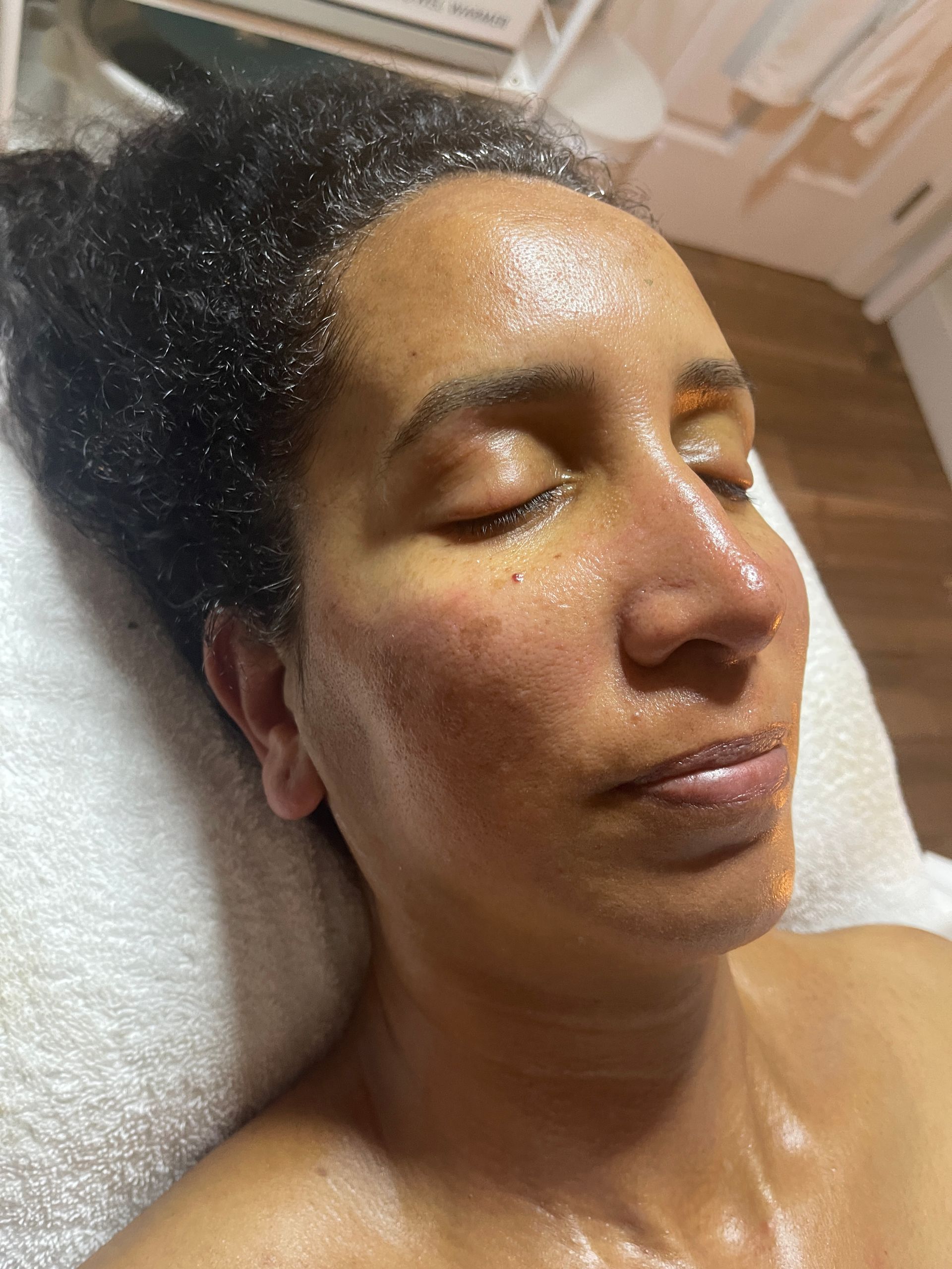 A woman is laying on a bed with her eyes closed and her face is covered in sweat.