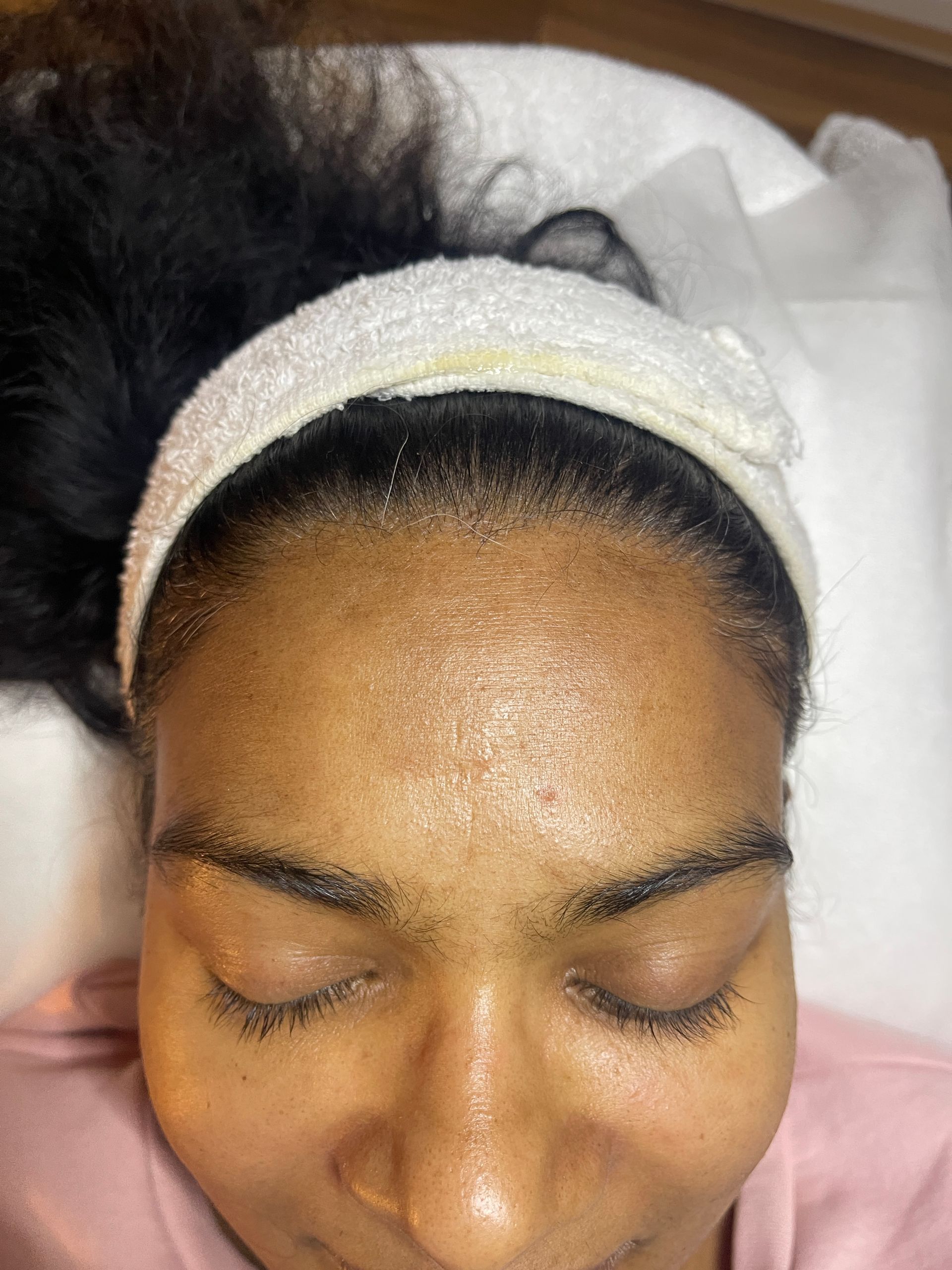 A woman is laying on a bed with her eyes closed and a headband on her head.