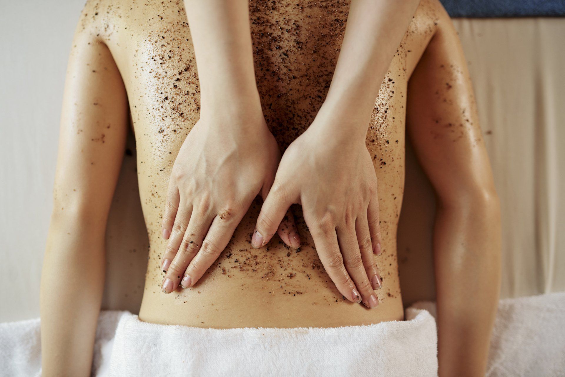 A woman is giving a man a body scrub at a spa.