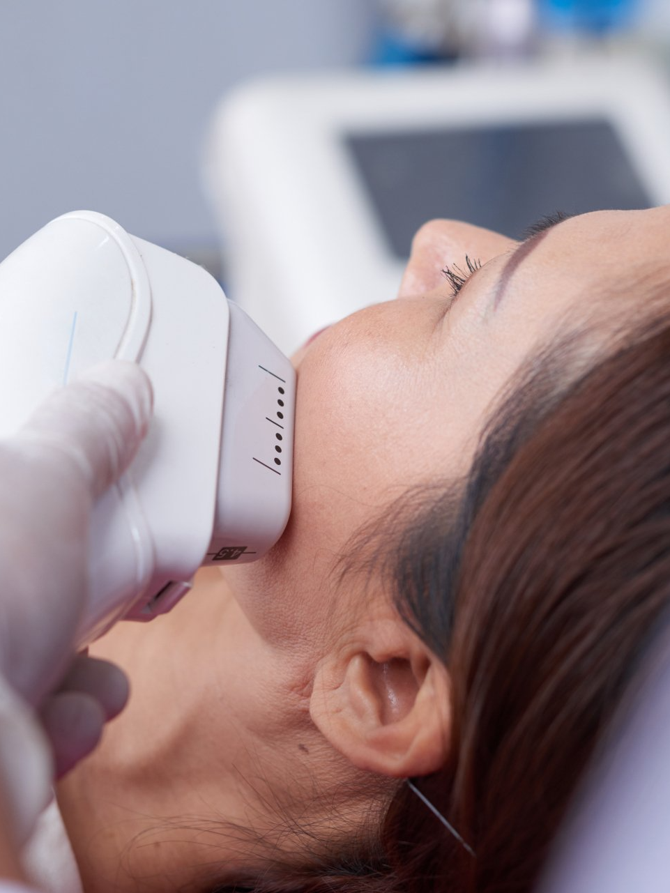 A woman is getting an ultrasound treatment on her face