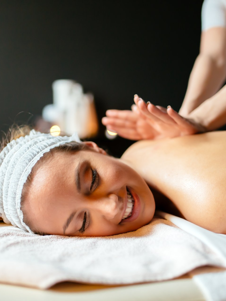 A woman is smiling while getting a massage at a spa