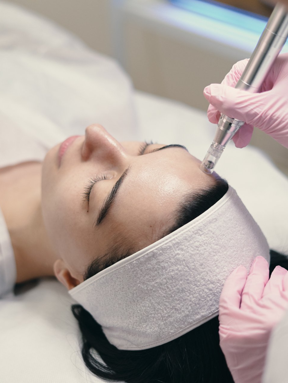 A woman is getting a facial treatment with a pen on her forehead.