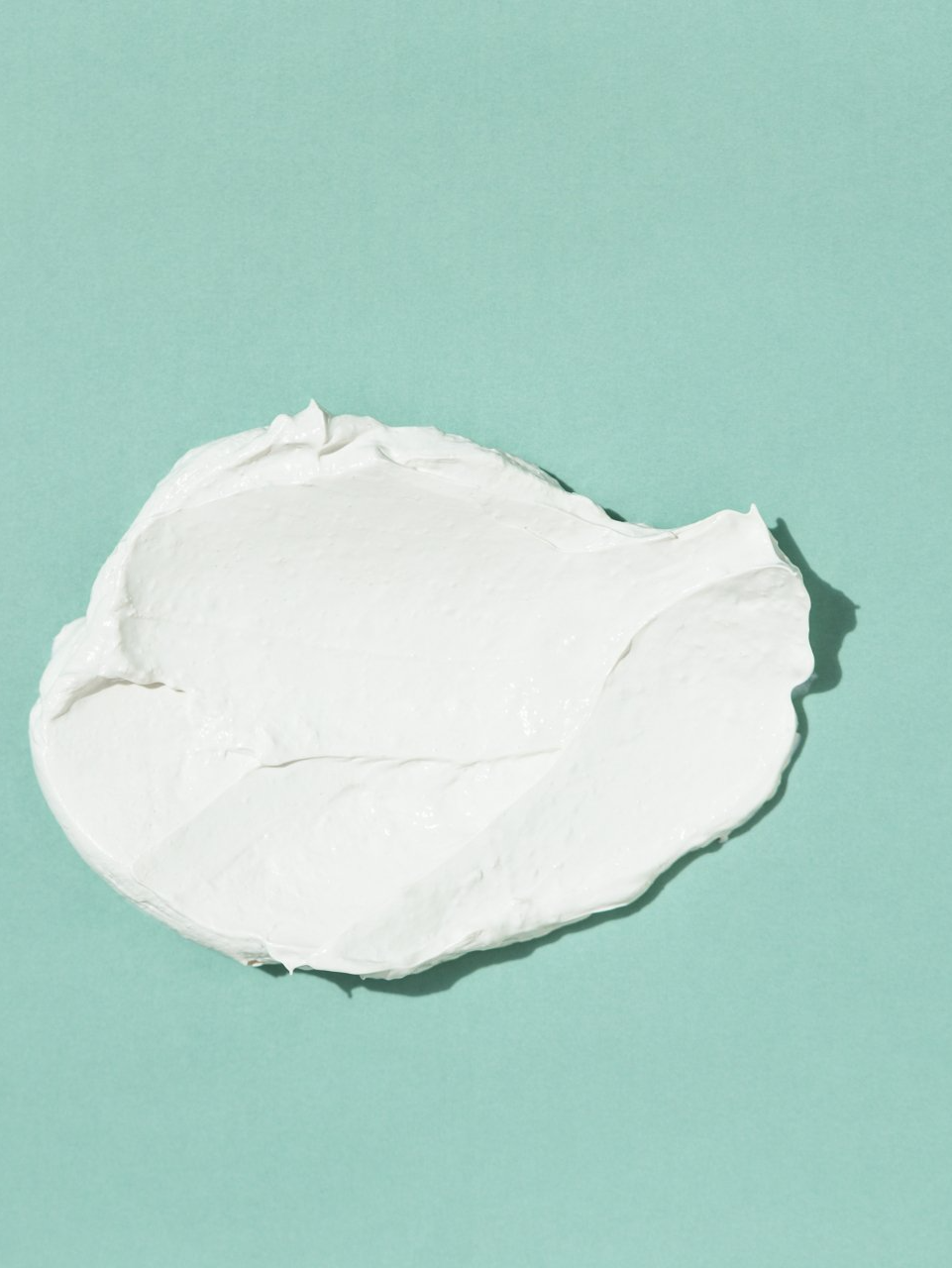 A swatch of white cream on a blue surface.