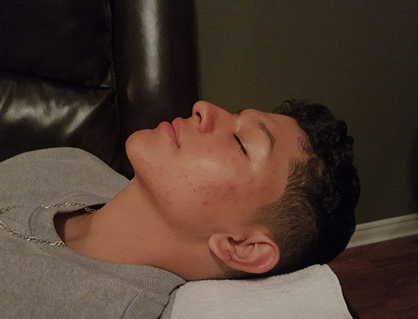 A young man is laying on a couch with his eyes closed