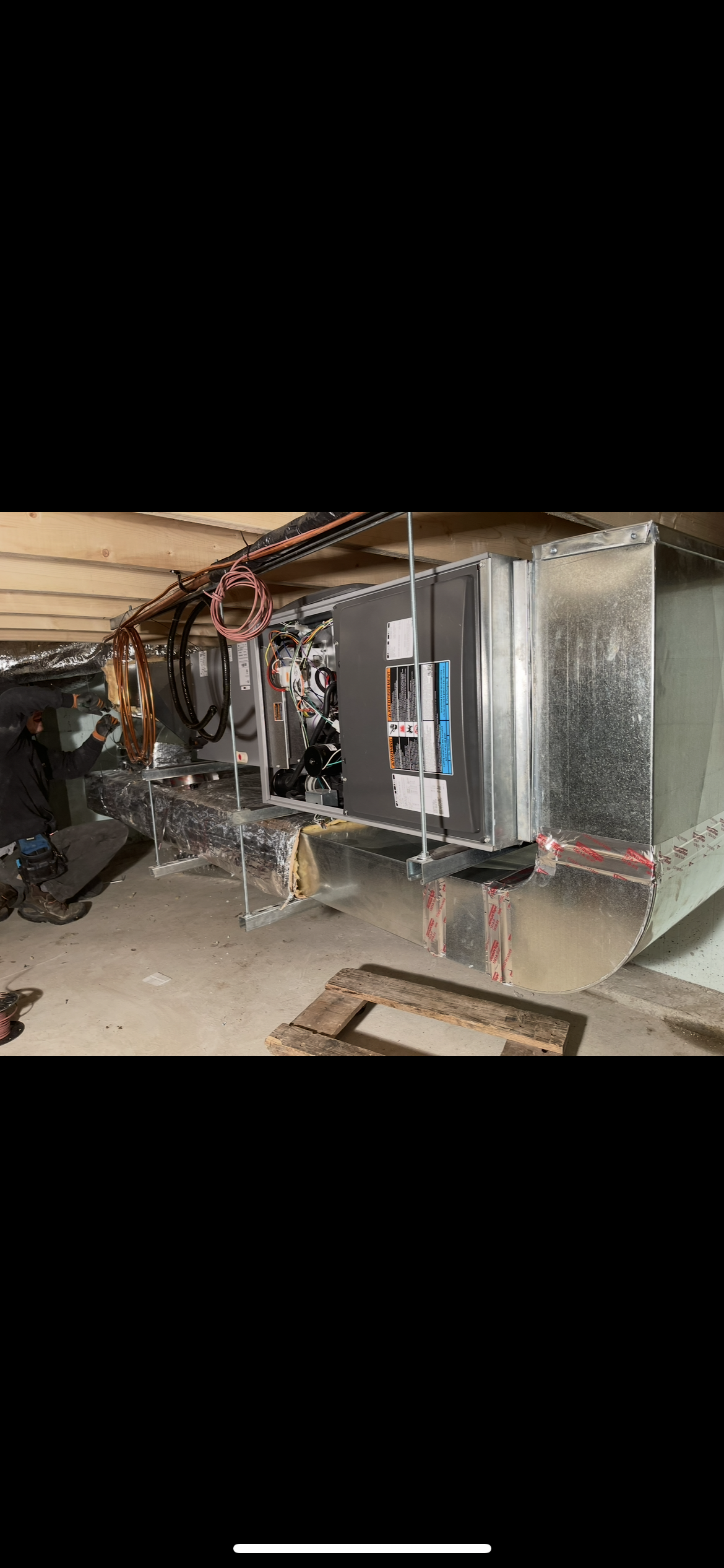 Interior of a crawl space showing newly installed galvanized metal HVAC ductwork and connected wires.