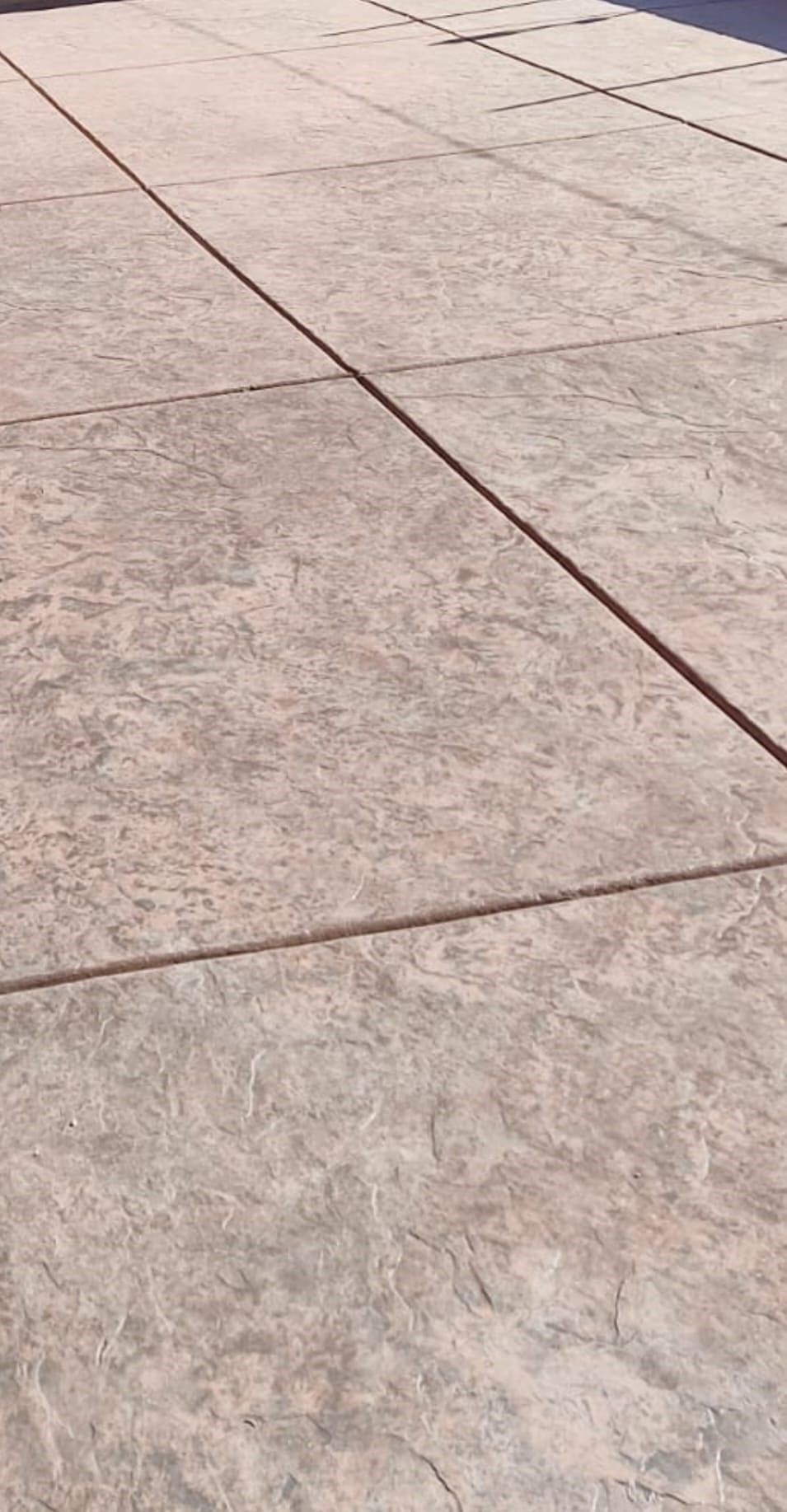 A close-up view of textured, light-colored concrete pavers arranged in a grid pattern on a walkway.
