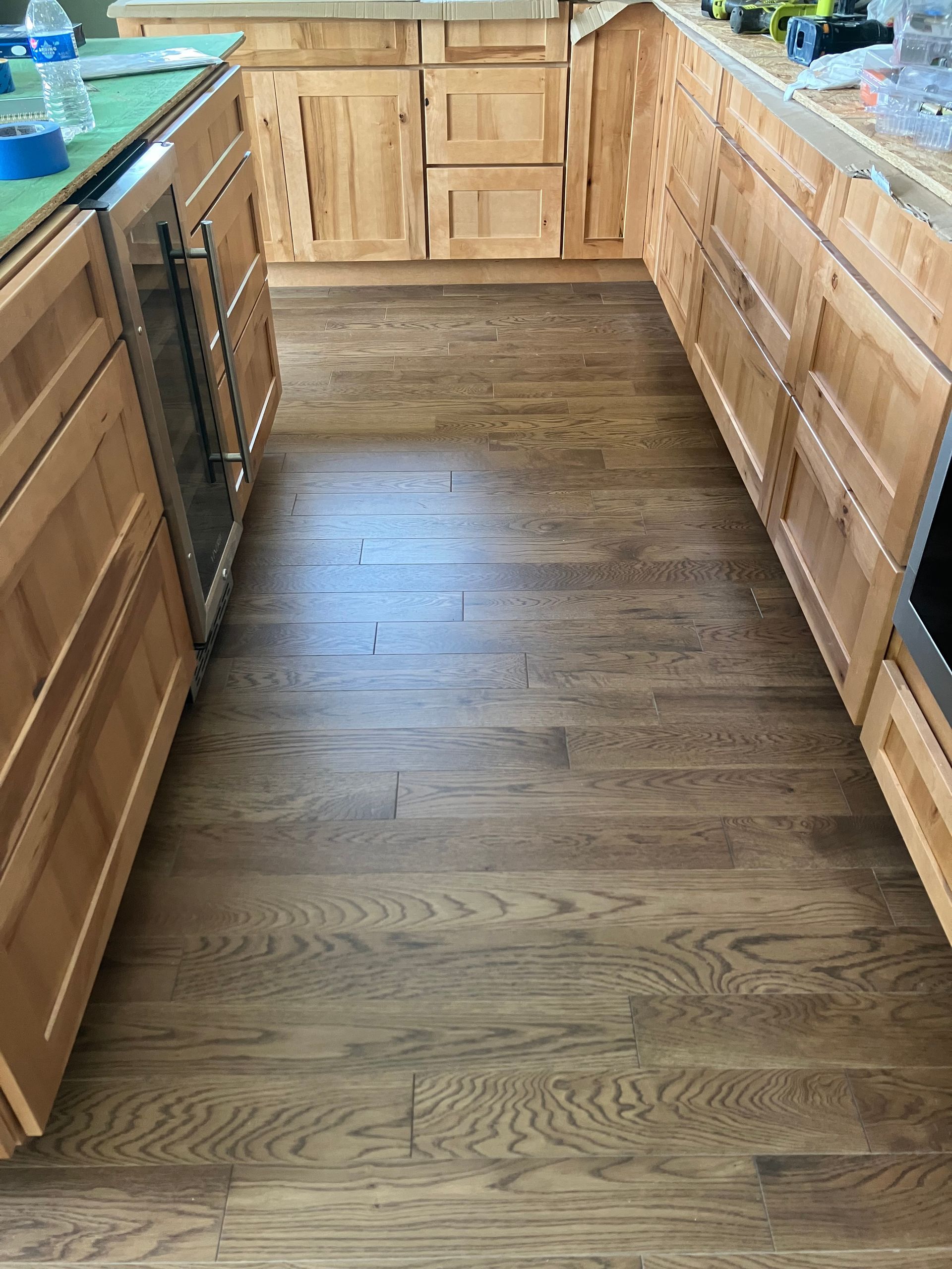 Narrow kitchen aisle with wood cabinets, hardwood floor, and granite countertops on both sides