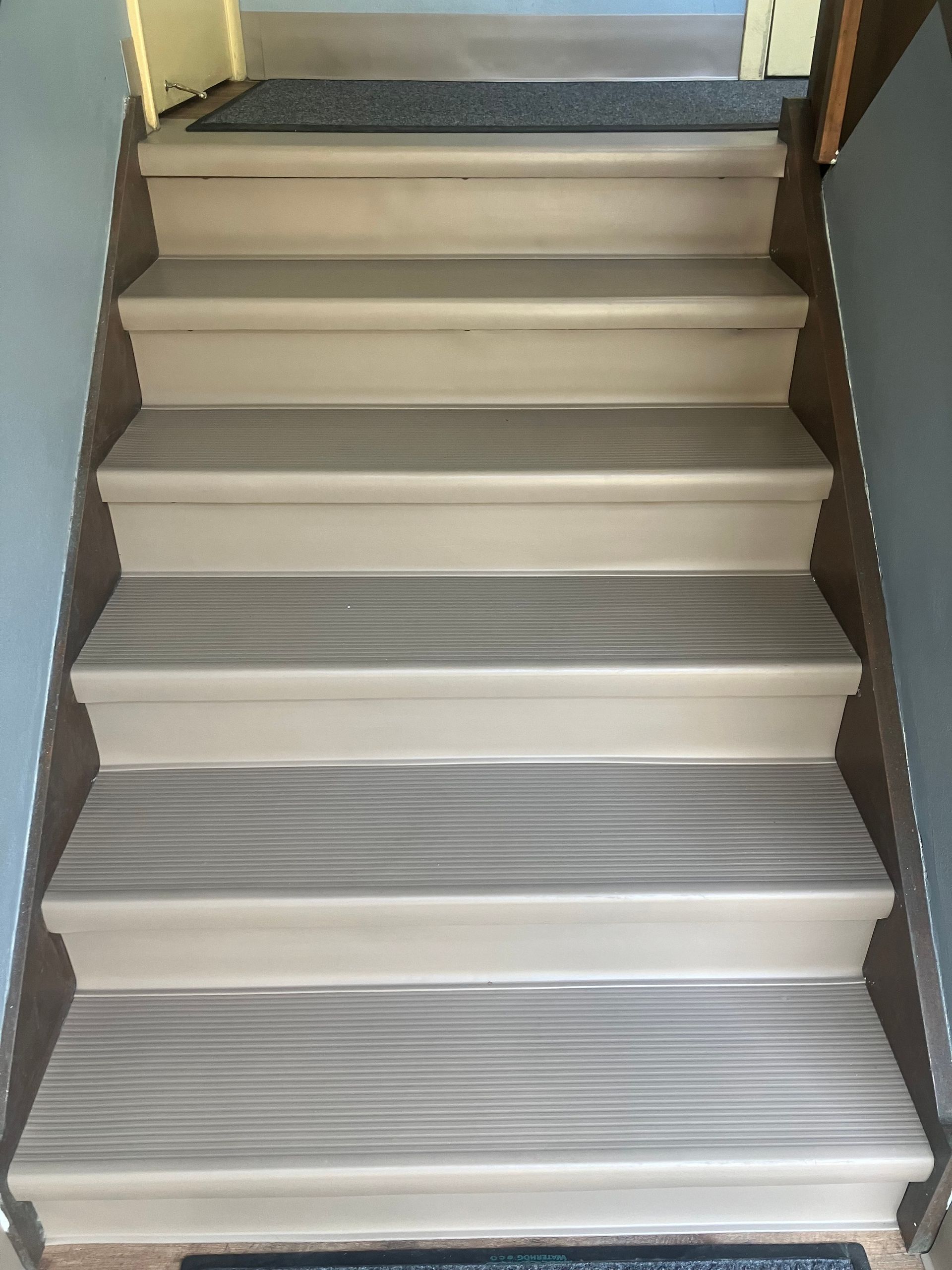 Indoor staircase with beige steps and gray anti-slip treads leading upward