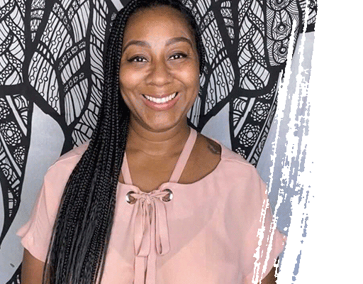 Woman with long braided hair, wearing a pink top, smiles at the camera. Black and white tree design backdrop.