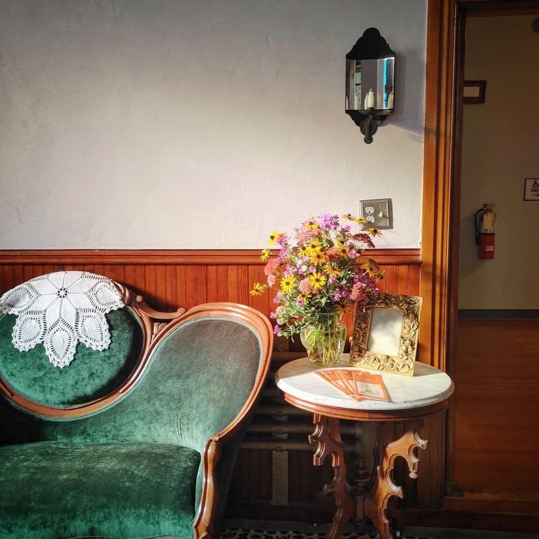 A green chair sits next to a small table with flowers on it