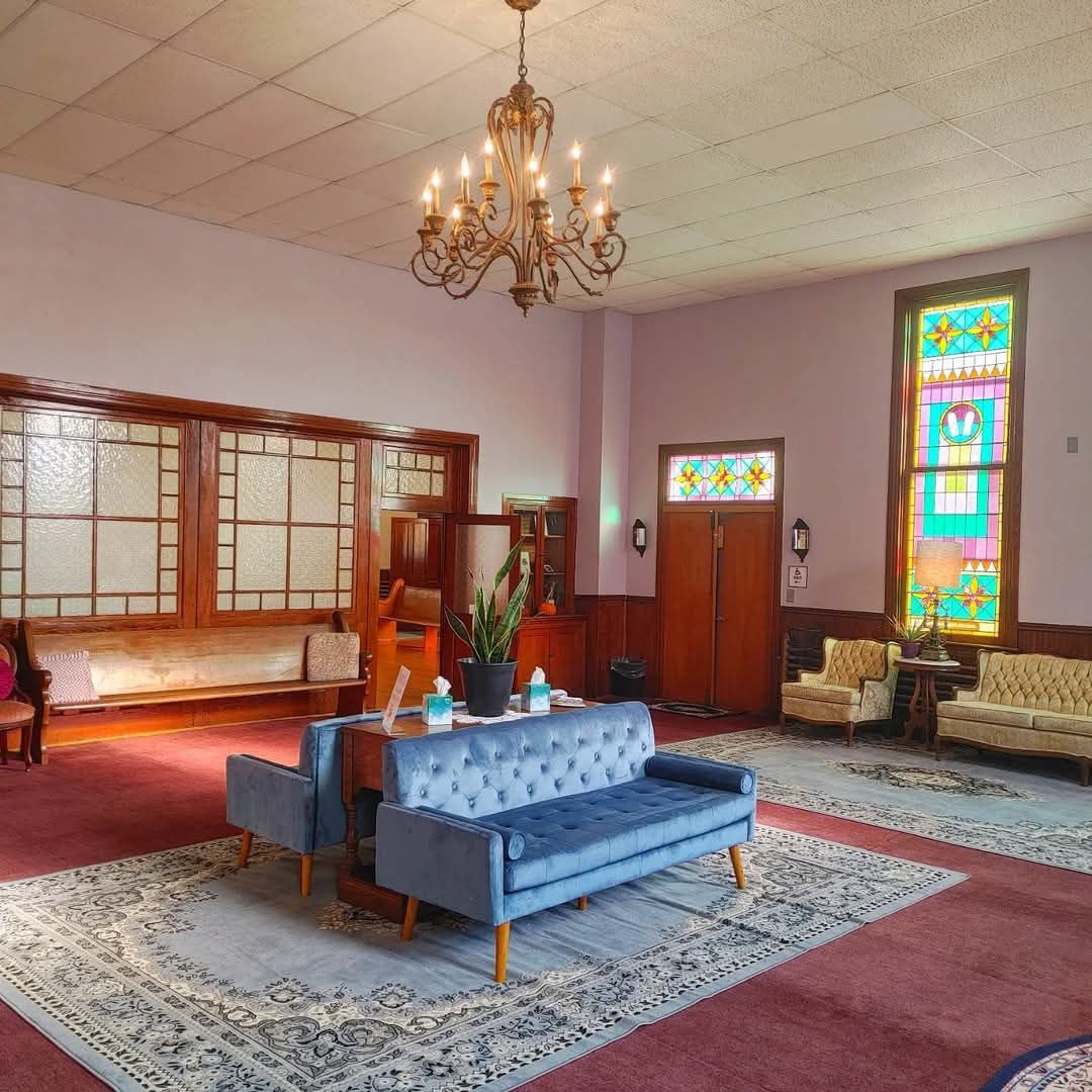 A living room with a couch and chairs and a stained glass window