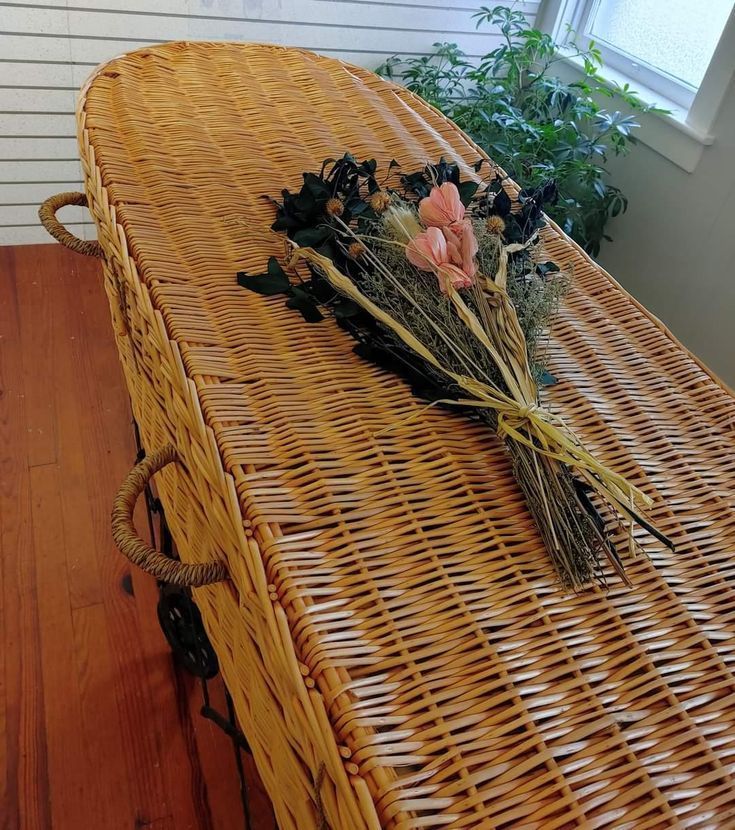 A wicker coffin with a bouquet of flowers on it