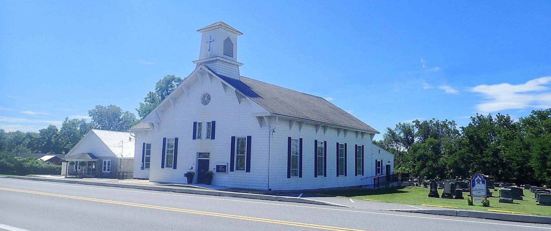 A white church is sitting on the side of the road.